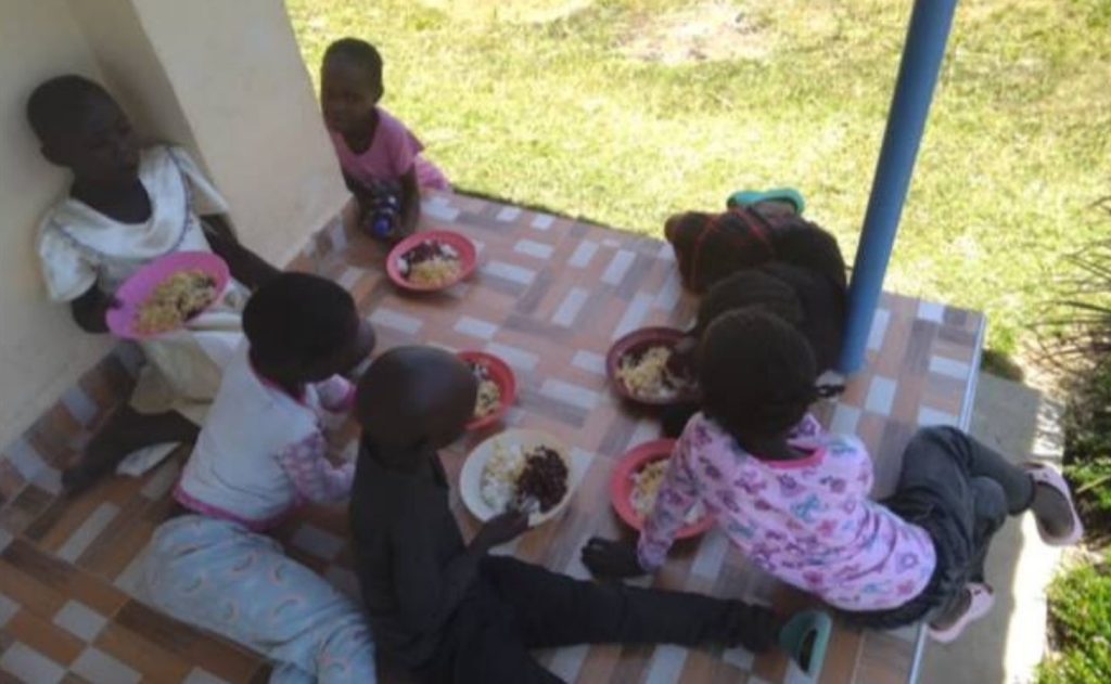 Happy Kujenga Inclusive Education students enjoying a nutritious free meal prepared with food grown in the school garden.
