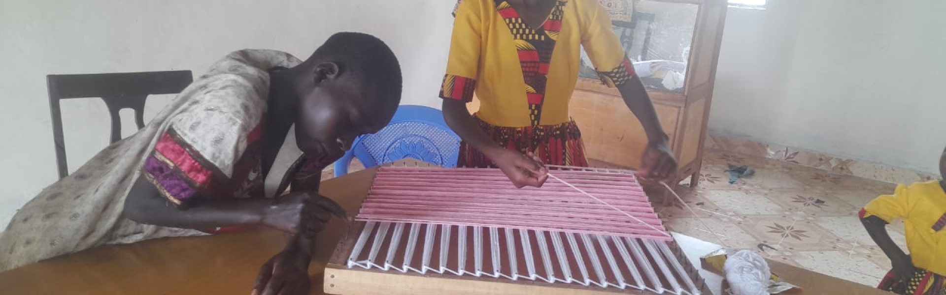 A student's hands carefully manipulating threads on an adaptive loom, mastering the weaving craft